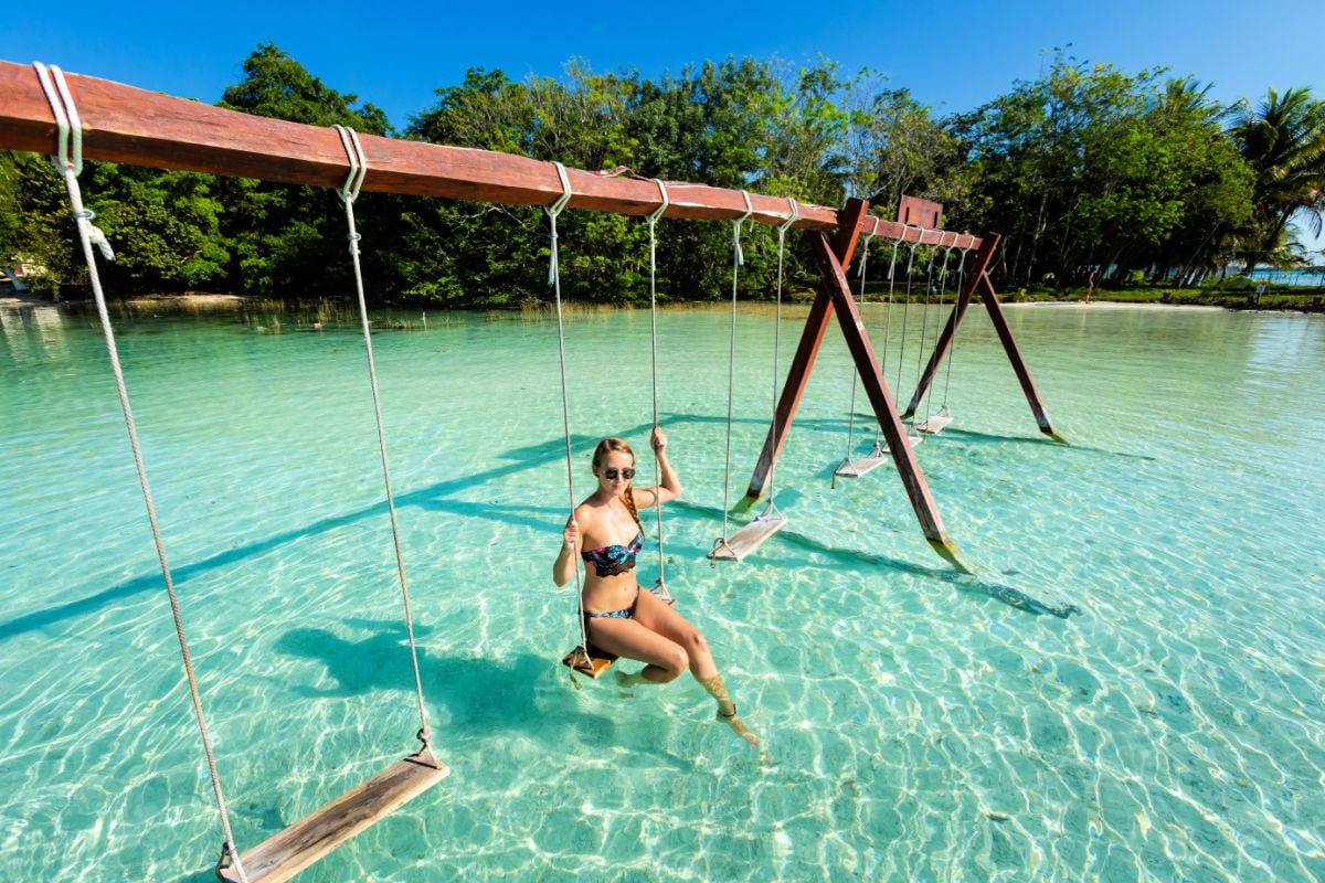 Woman in lake Bacalar on a swing